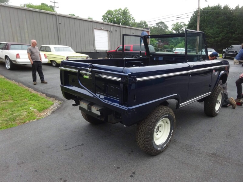 Here's an alt tag for the image: Dark blue Ford Bronco undergoing restoration.