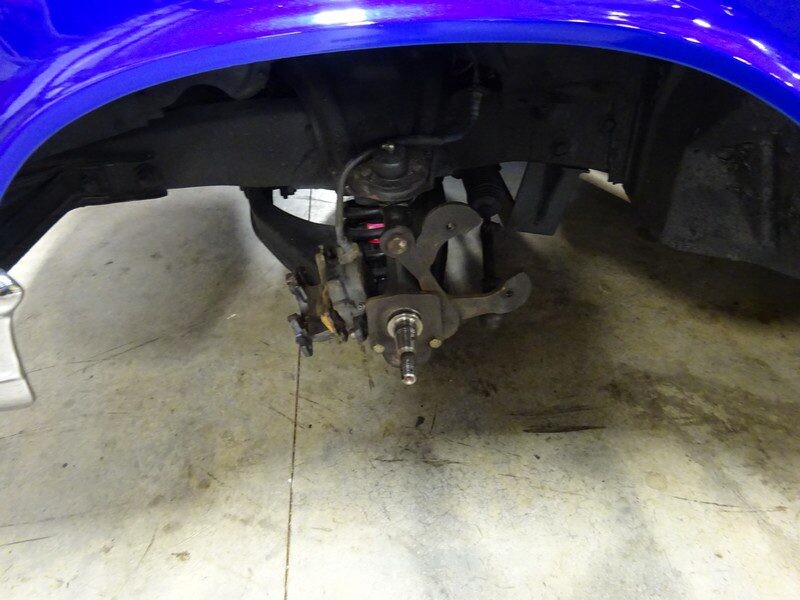 Here's an 8-word alt tag for the image: Blue car's front suspension and brake assembly.