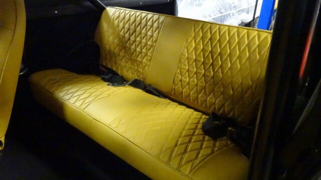 Here's an 8-word alt tag for the image: Yellow diamond-tufted back seat in classic car.