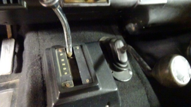 Here's an alt tag for the image: Classic car's gear shift and controls.
