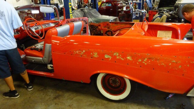 Red classic car undergoing restoration.