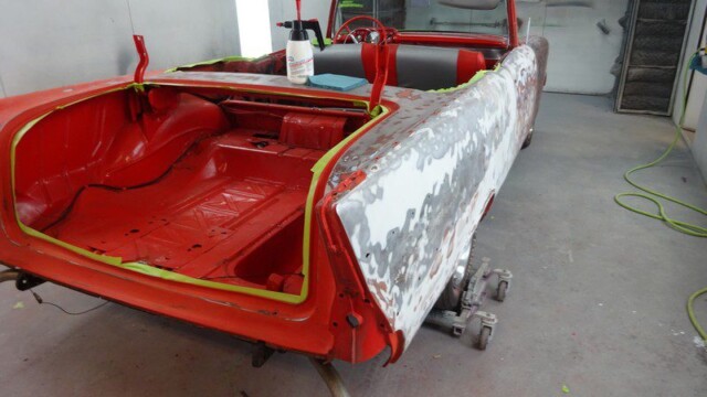 Red classic car body restoration in progress.