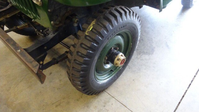 Green military Jeep front wheel closeup.