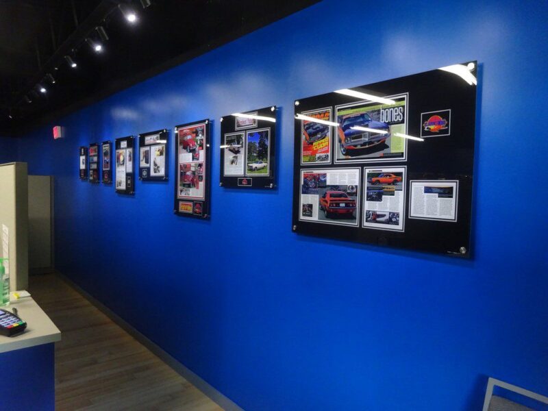 Wall of framed car magazine articles.