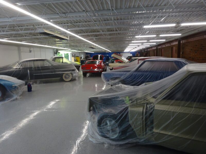 Classic cars covered in plastic sheets.