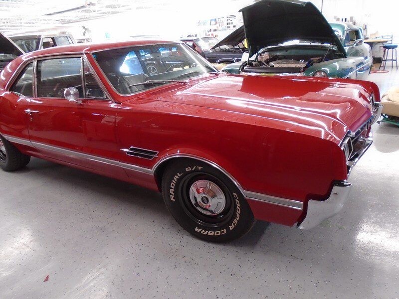 Red classic Oldsmobile Cutlass in garage.