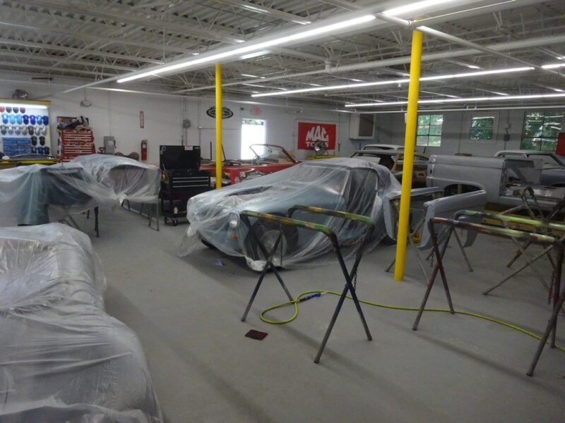 Cars covered in plastic in auto shop.
