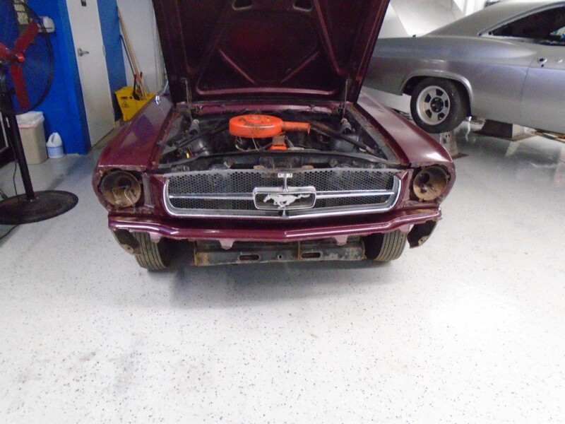 Here's an alt tag for the image: `Burgundy Ford Mustang under repair`