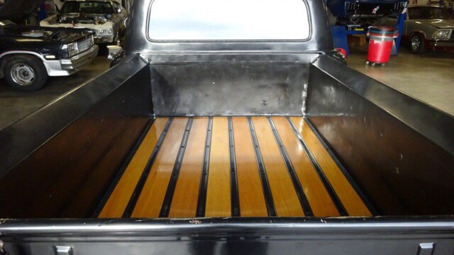 Black Ford truck bed with wood planks.