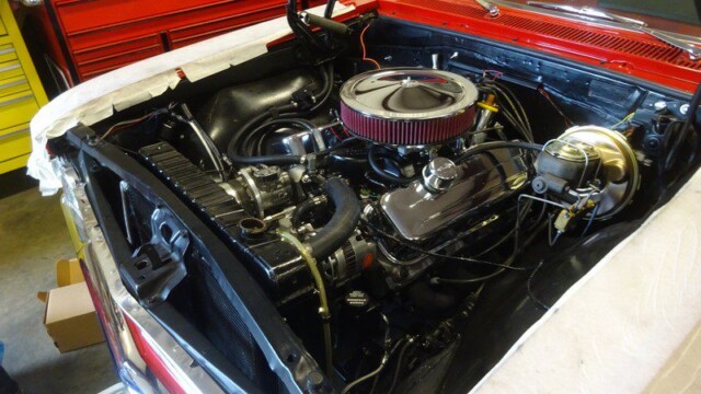 Open hood of vintage red car showing engine