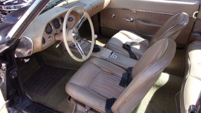 Classic car's tan interior and steering wheel.