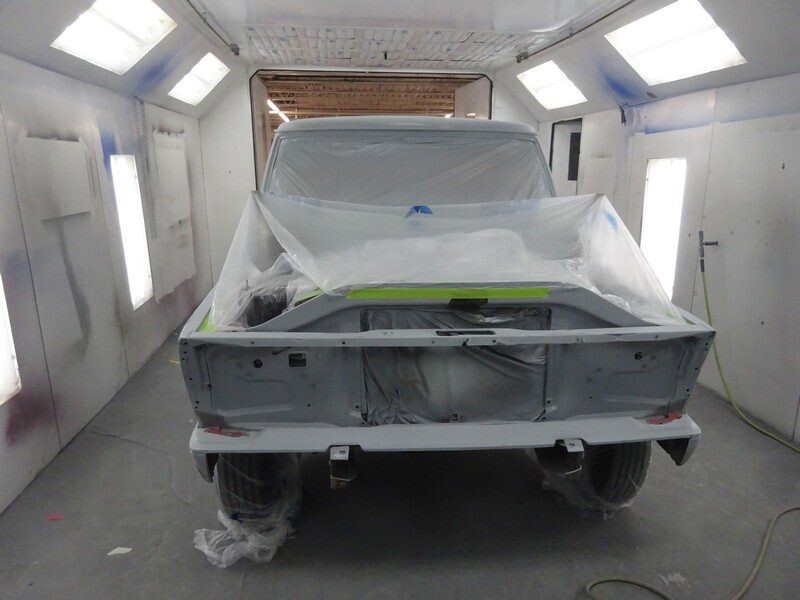 Here's an alt tag for the image: Primed truck in paint booth.