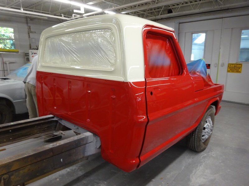 Red and cream Ford truck in paint shop.