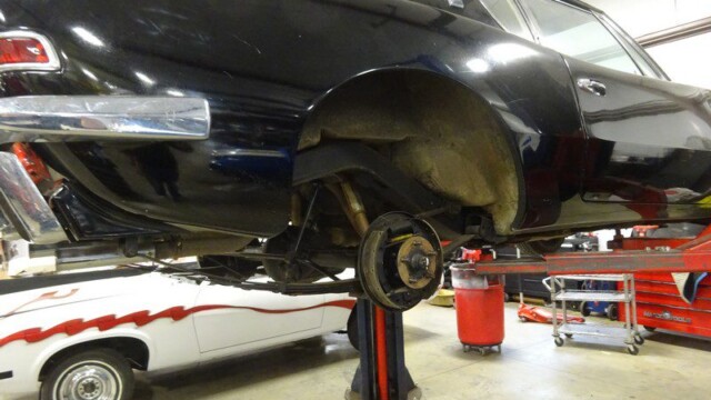 Black classic car on a lift.