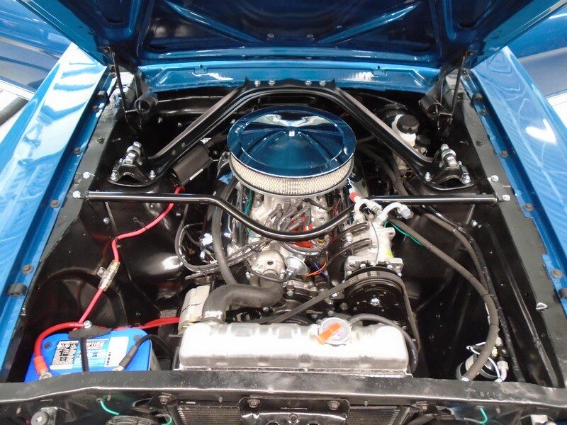Restored blue Mustang engine bay with strut brace
