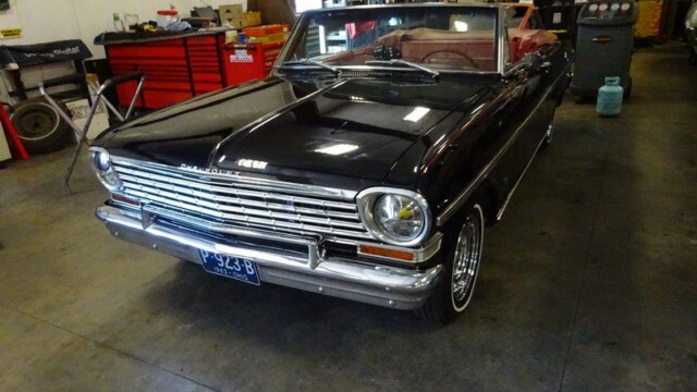 Black Chevrolet Nova convertible in garage.