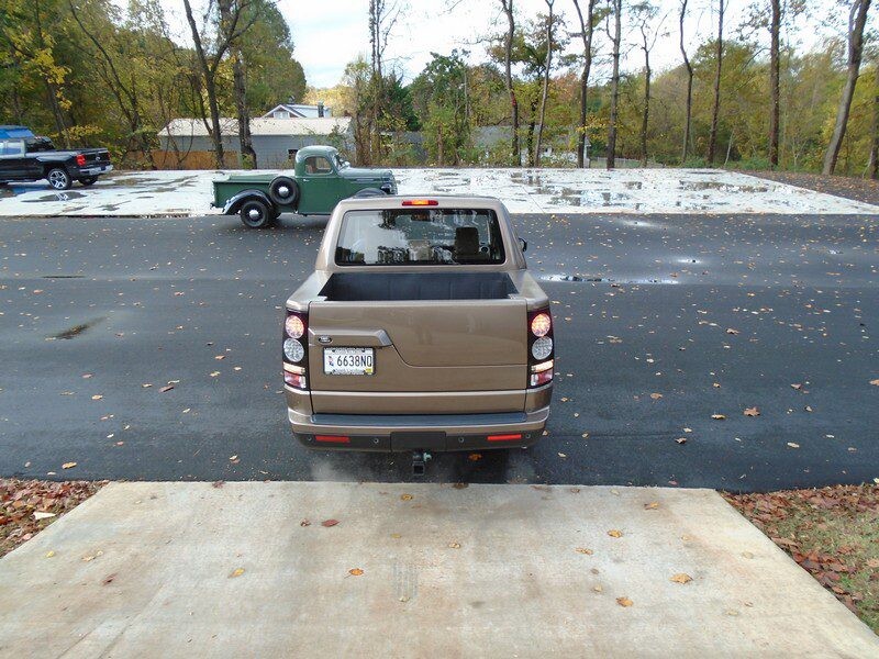 Rear view of a tan Land Rover pickup truck.