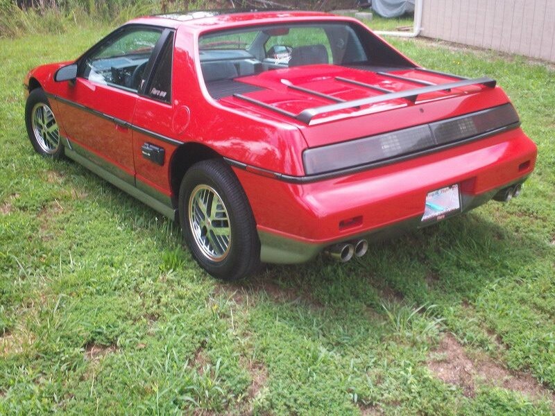 Red Pontiac Trans Am parked on grass.