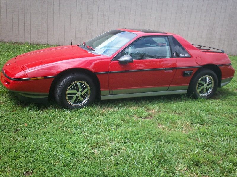 Red Pontiac Firebird Trans Am on grass.