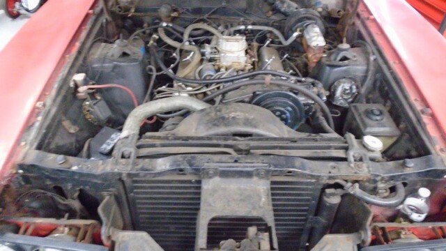 Here's an 8-word alt tag for the image: Red classic car engine bay, open hood.