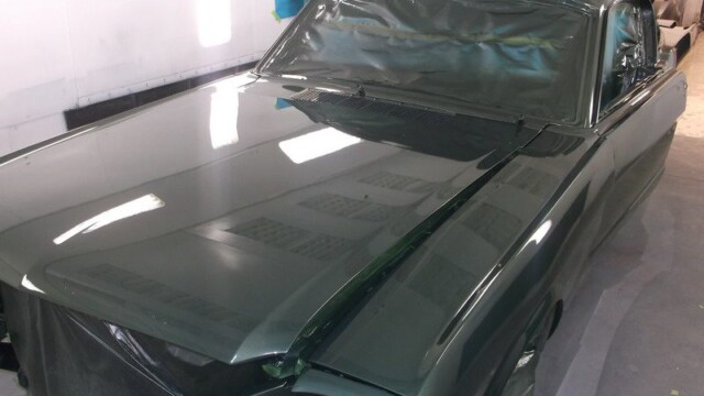 Dark green classic car in paint booth.