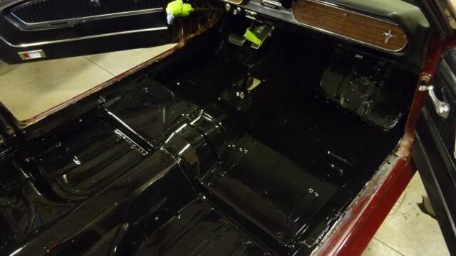 Here's an alt text suggestion: Black painted floor of classic car interior.