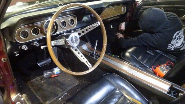 Mechanic working inside classic Mustang cabin