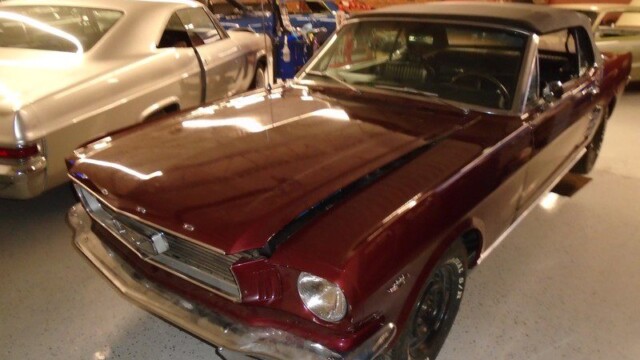 Here's an 8-word alt tag for the image: Burgundy Ford Mustang convertible classic car in garage.