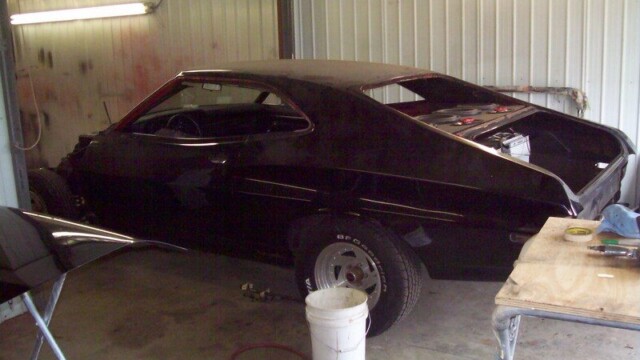Black Ford Torino in auto body shop.