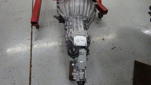 Here's an alt tag for the image: `Car transmission on shop floor`