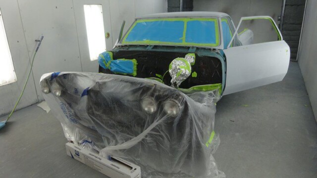 Car in paint booth, masked for paint.