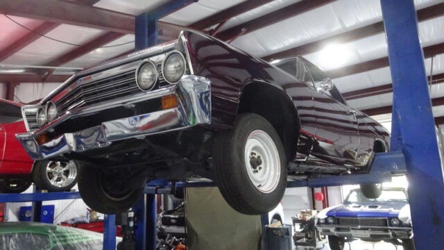 Maroon vintage muscle car raised on lift