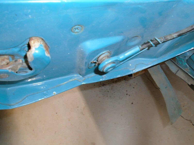 Here's an alt tag for the image: Blue car door, rusted latch, cable.