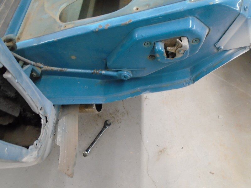 Blue car door repair, wrench nearby.