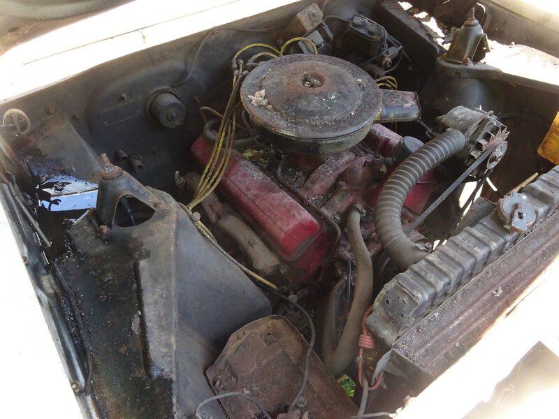 Here's an alt tag for the image: Rusty classic car engine bay.