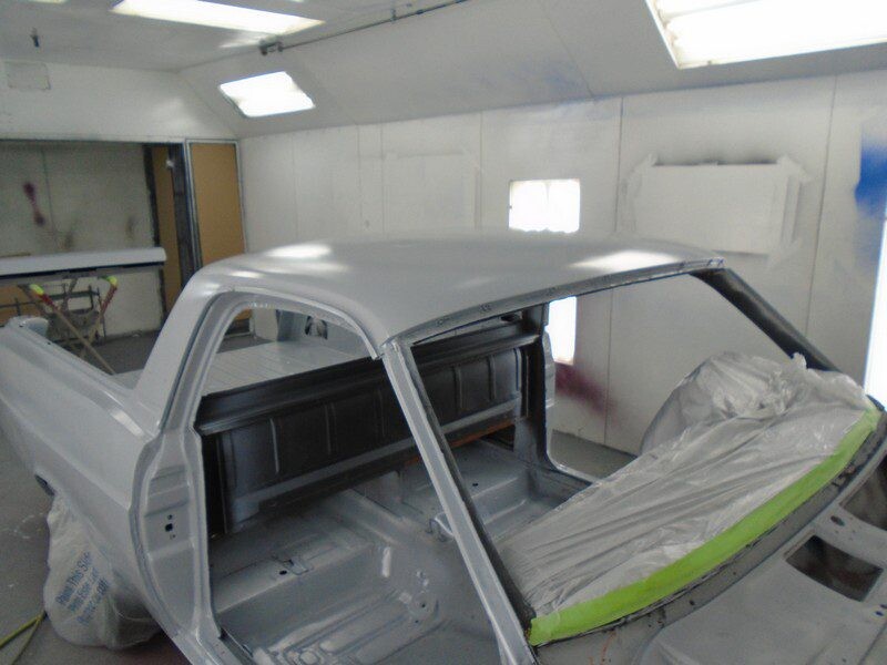 Primered classic car body in paint booth.