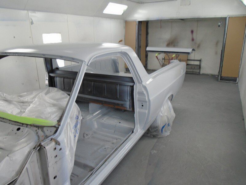 Primered classic car in paint booth.