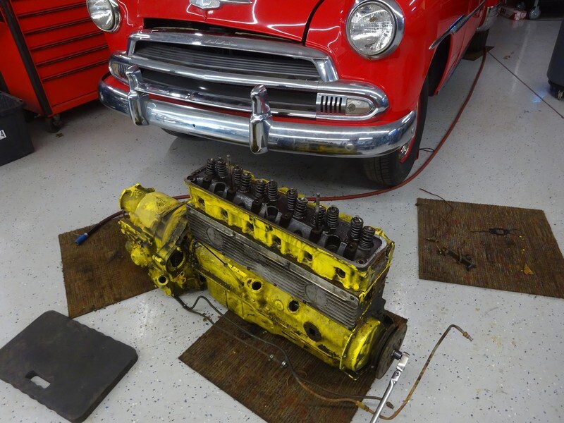Disassembled car engine on garage floor.