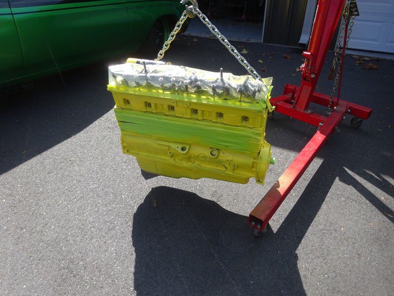 Painted engine block hanging from hoist.