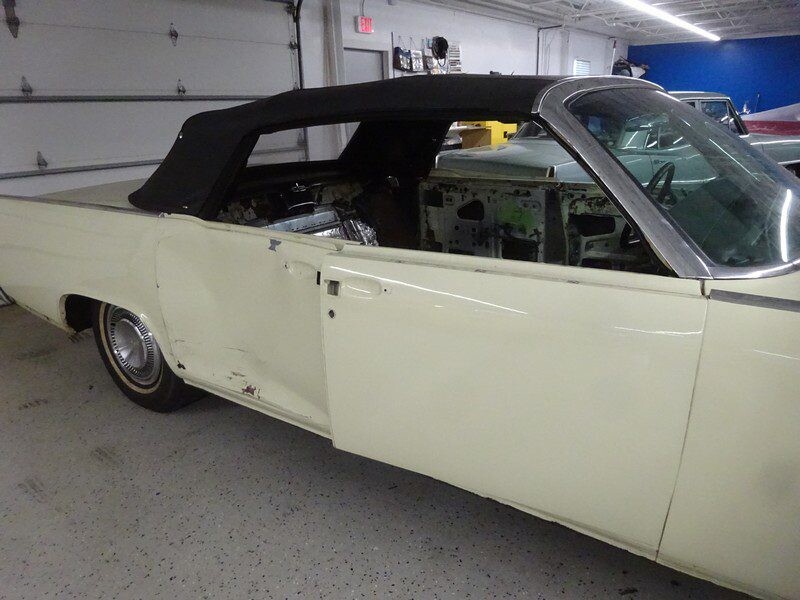 Cream-colored convertible classic car in garage.