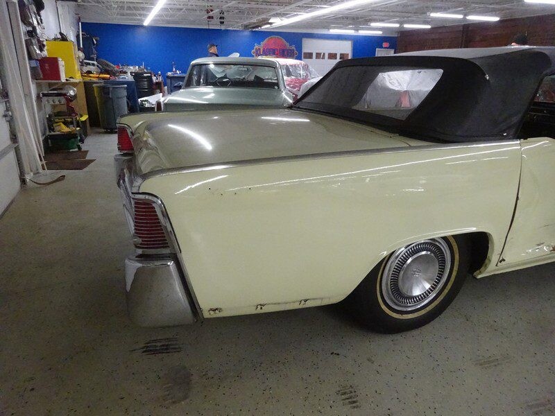 Beige classic convertible car in garage.