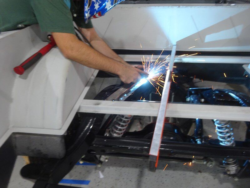 Welder fabricating vehicle frame sparks.