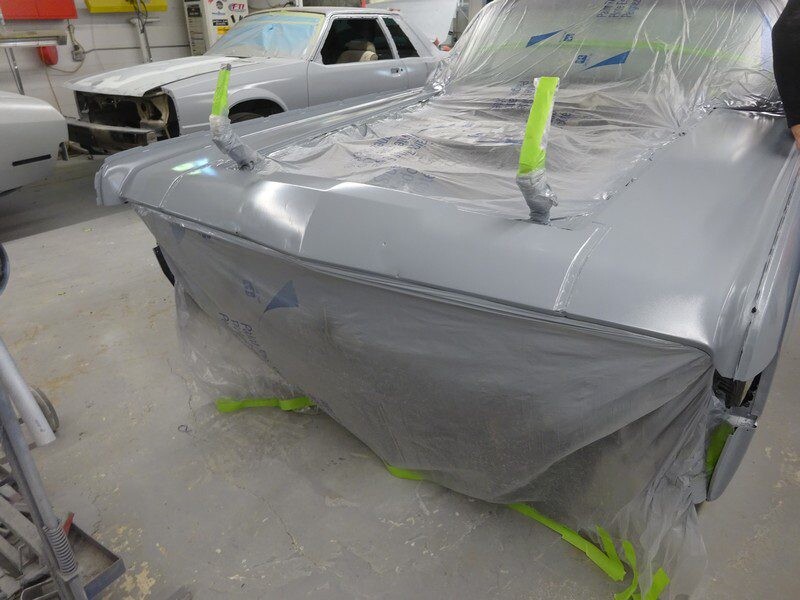 Gray car in auto body shop, paint masked.