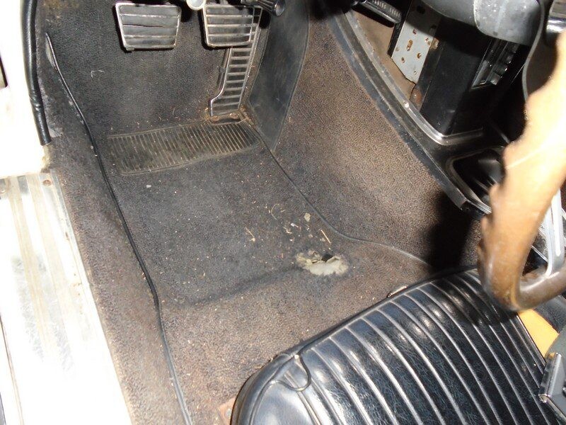 Dirty car floor mat with hole.