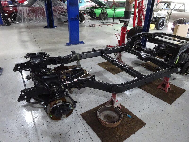 Car chassis on jack stands in shop.