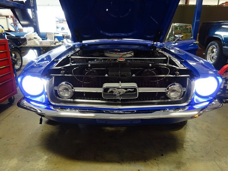 Blue Mustang with bright headlights.