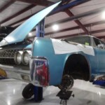 Here's an 8-word alt tag for the image: Blue classic car undergoing restoration in garage.