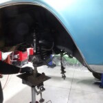 Mechanic repairing classic car suspension.