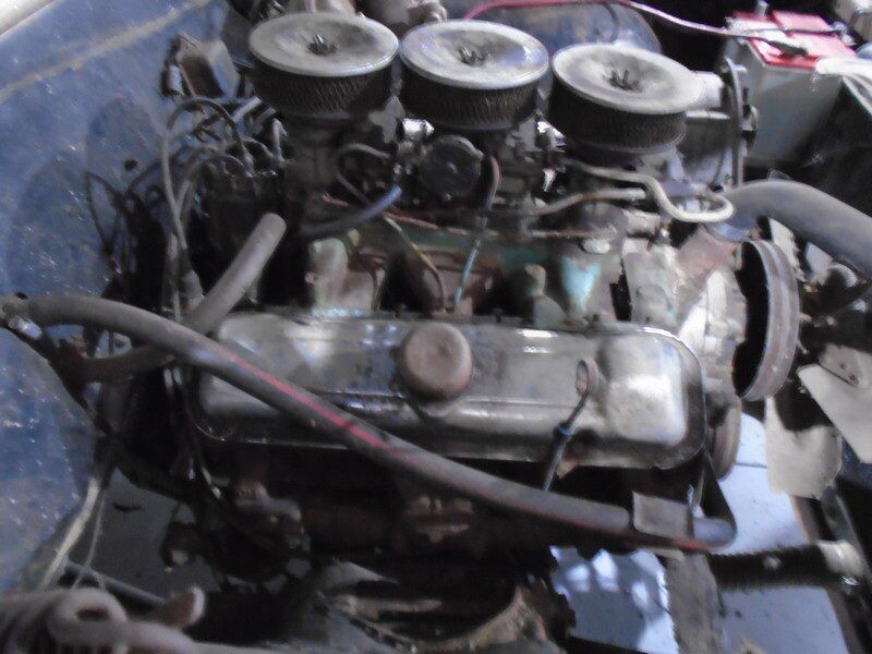 Here's an alt tag for the image: Old, rusty V8 car engine.