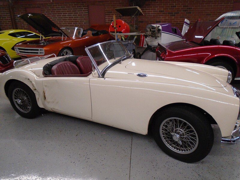 Cream-colored classic MG roadster in garage.